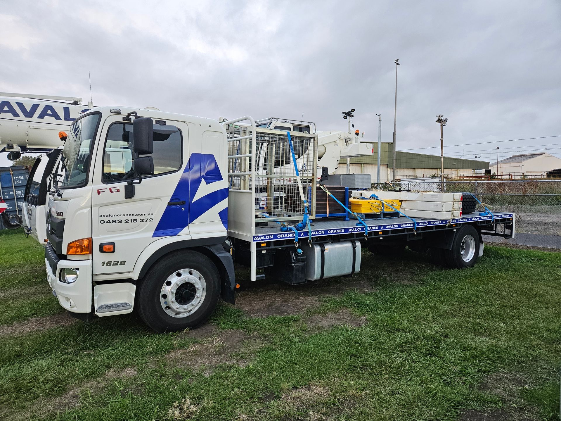 A white truck with a blue crane on the back is parked in a parking lot.