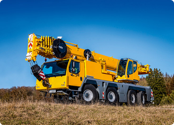 A large yellow crane is parked in a field.