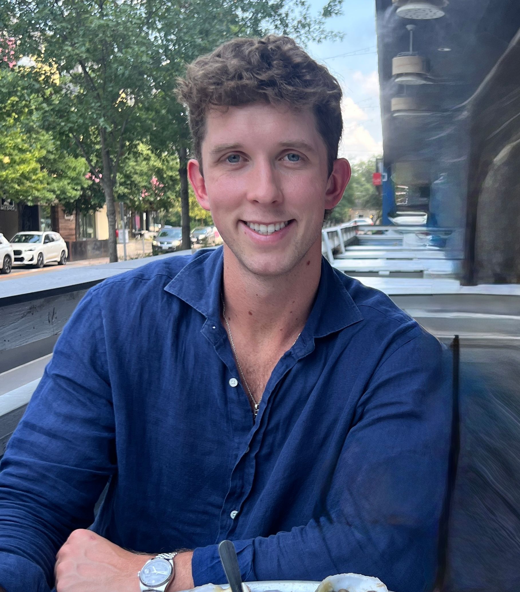 Man in brown bomber jacket and cap crossing street in Tokyo.