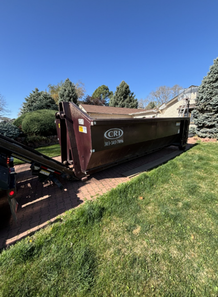 Construction site dumpster rental with roll-off container placed on residential driveway in Denver.