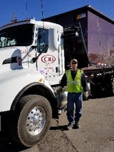 Truck delivering large roll off dumpster for disposal.