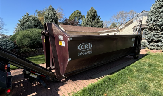 Large roll off dumpster being placed on a residential driveway. Large roll off dumpster being placed on a residential driveway.