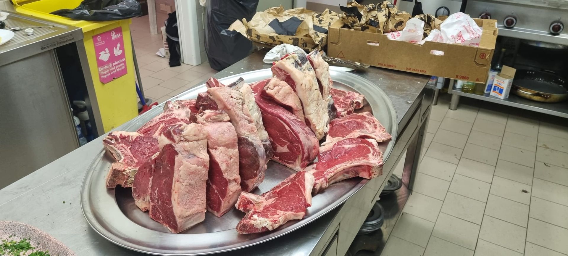 Tagli di carne cruda disposti su un piatto d'argento in una cucina.