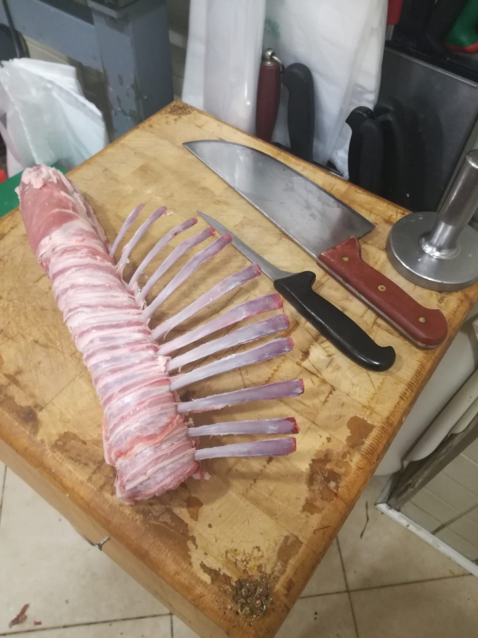 Carré di agnello con due coltelli su un ceppo di legno.