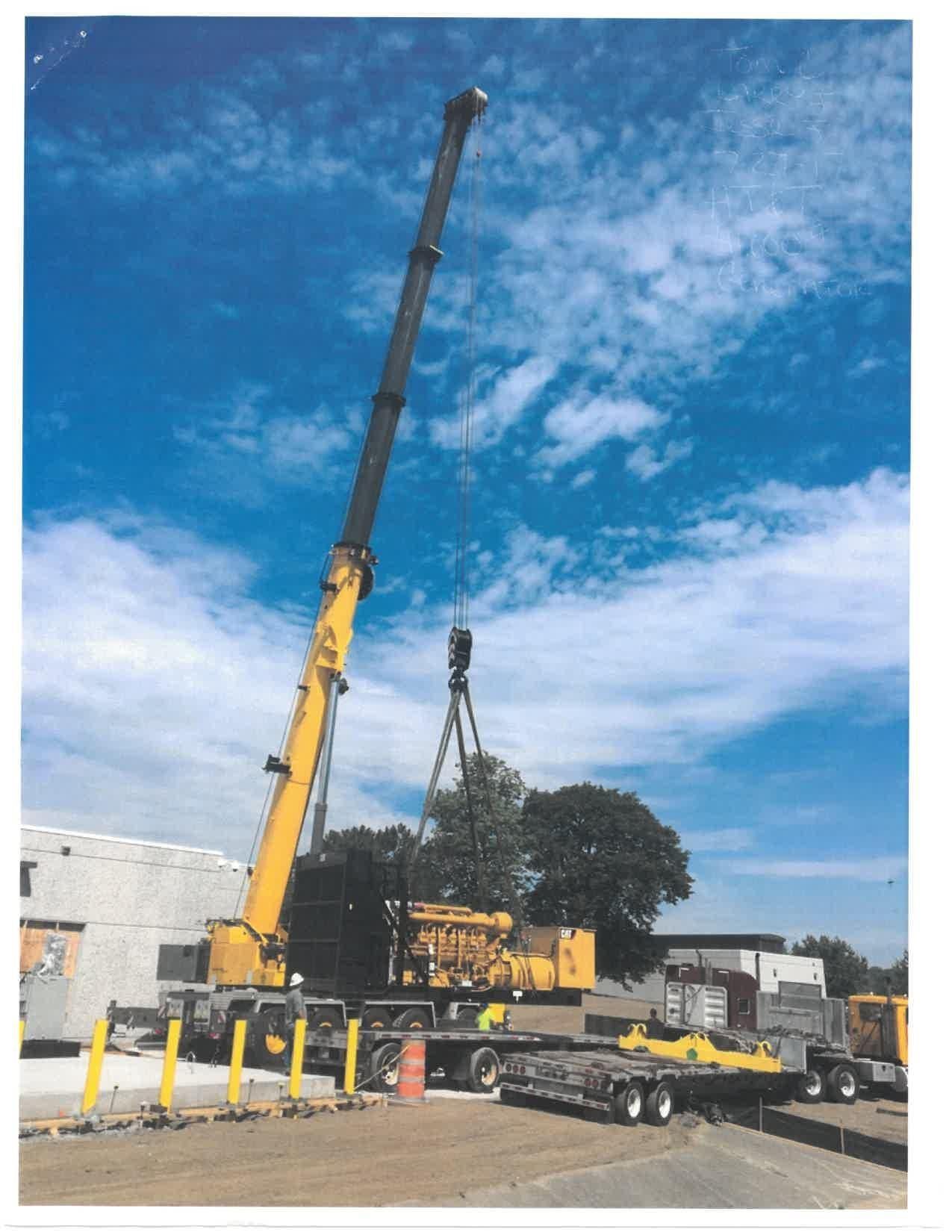 A Large Yellow Crane Is Lifting Something in Front of a Building — Akron, OH — Frank Lucco Company