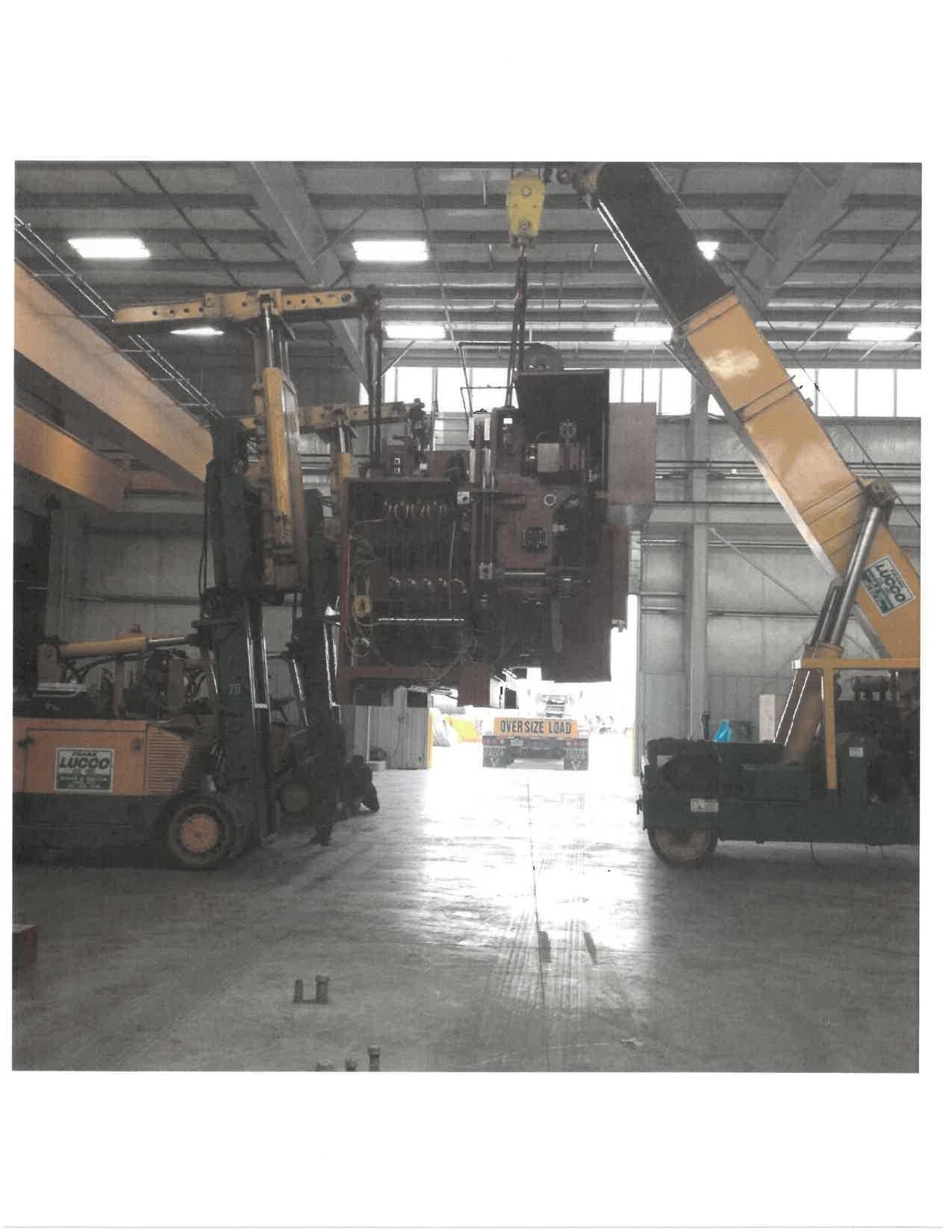 A Large Machine Is Being Lifted by a Crane in a Warehouse — Akron, OH — Frank Lucco Company
