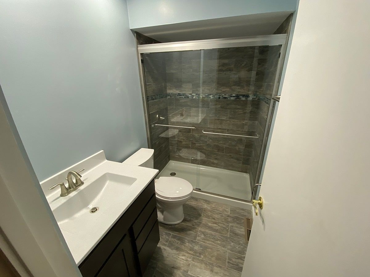 a bathroom with a toilet , sink and shower .