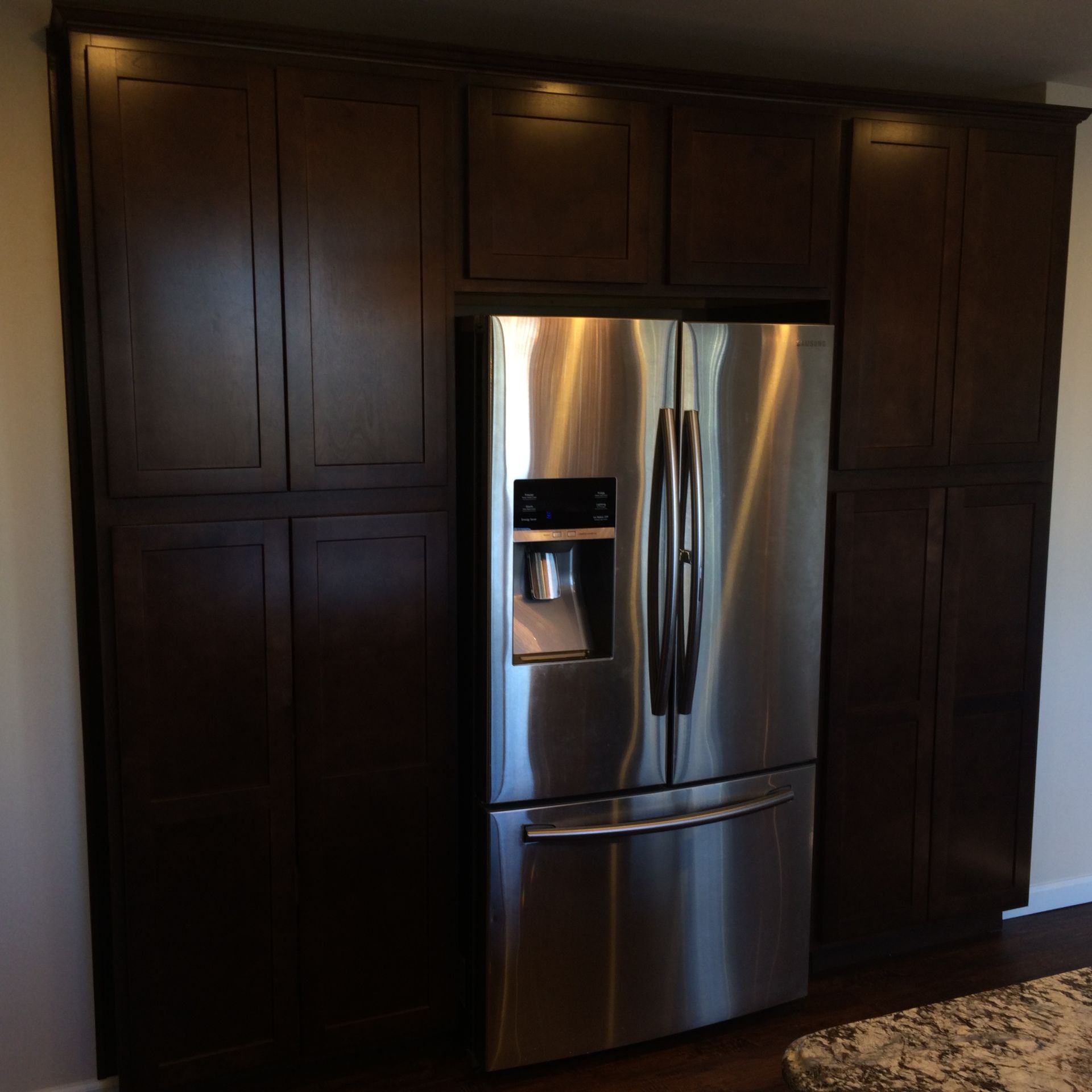 a stainless steel refrigerator in a kitchen with dark wood cabinets