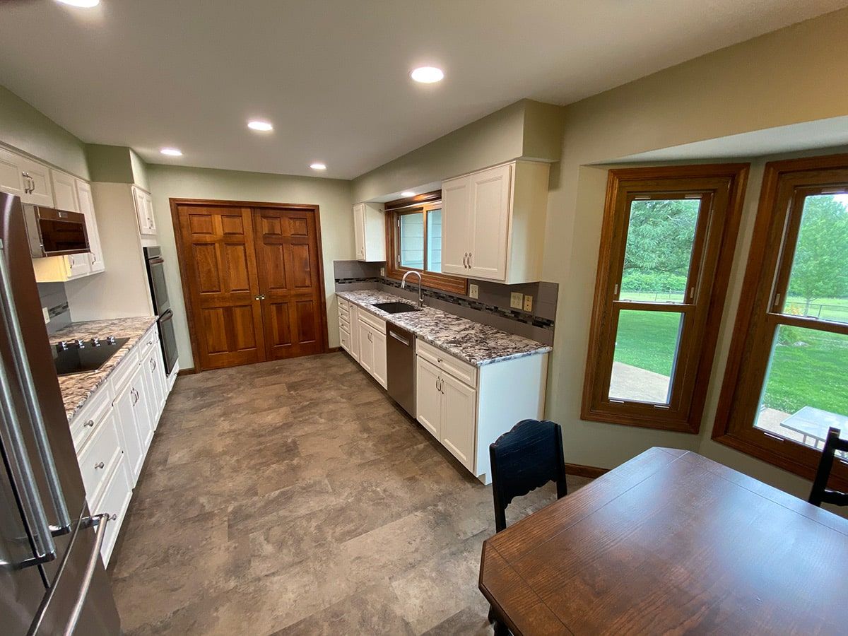 a kitchen with stainless steel appliances , granite counter tops , a table and chairs .