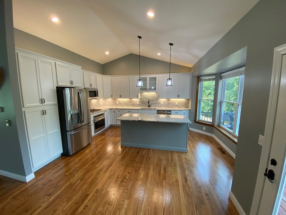 a kitchen with white cabinets , stainless steel appliances , and hardwood floors .