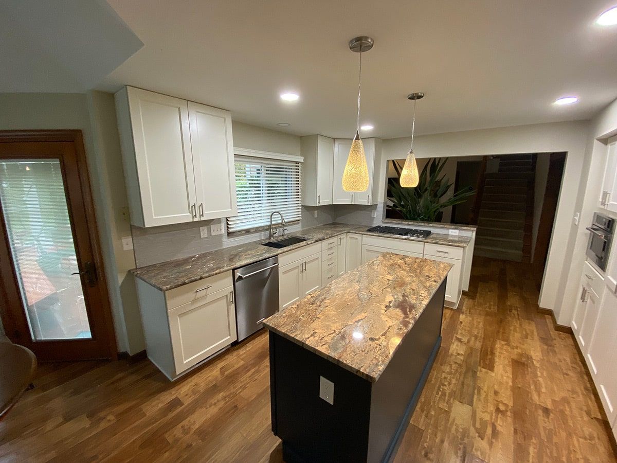 a kitchen with white cabinets , granite counter tops , stainless steel appliances and hardwood floors .