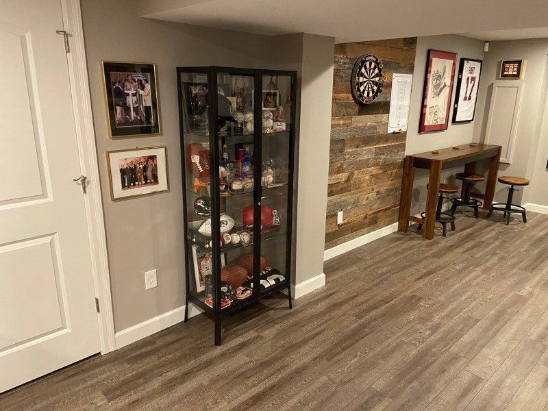 a basement with a glass cabinet and a dart board on the wall .