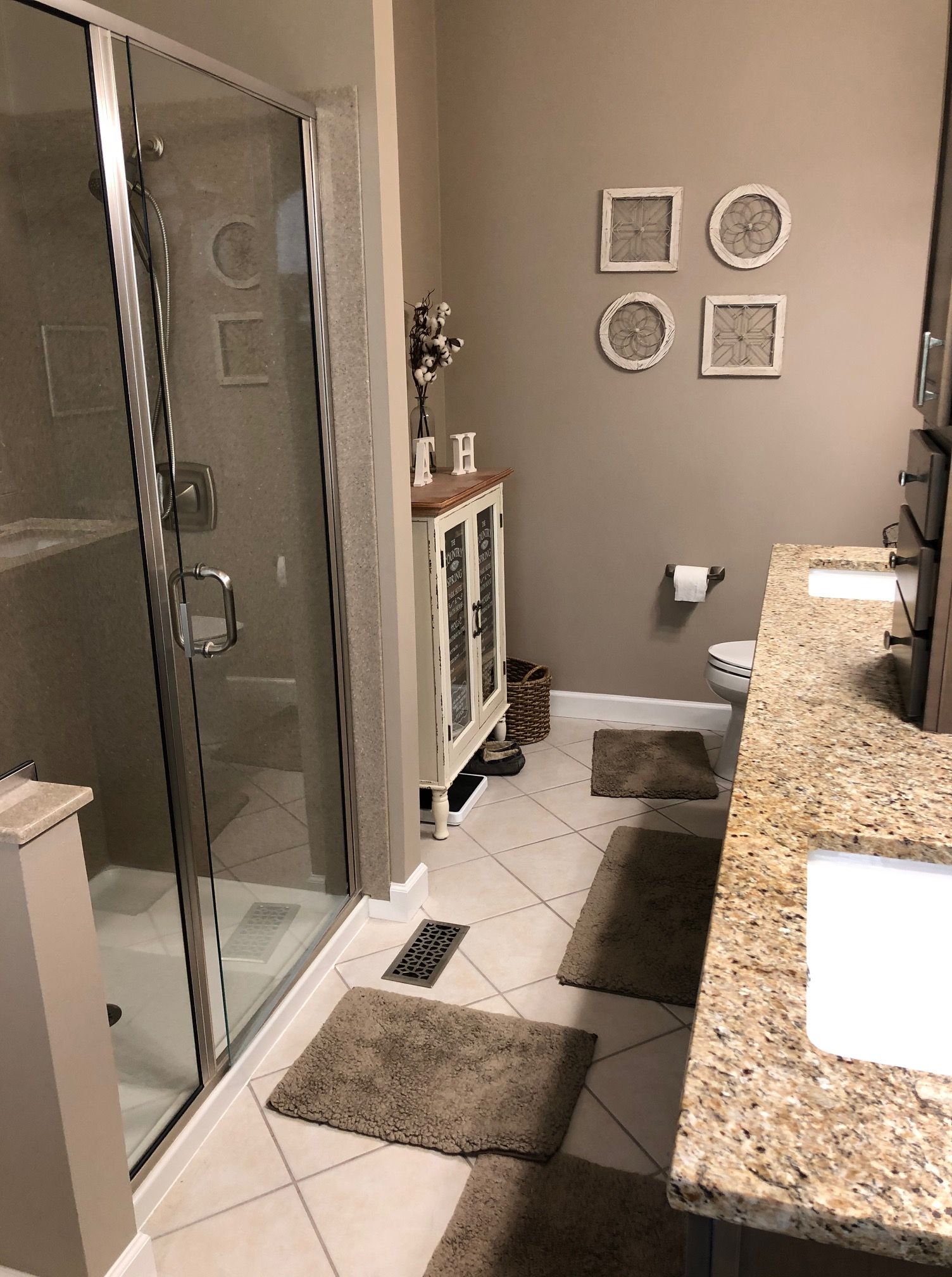 a bathroom with a walk in shower , two sinks , and a toilet .