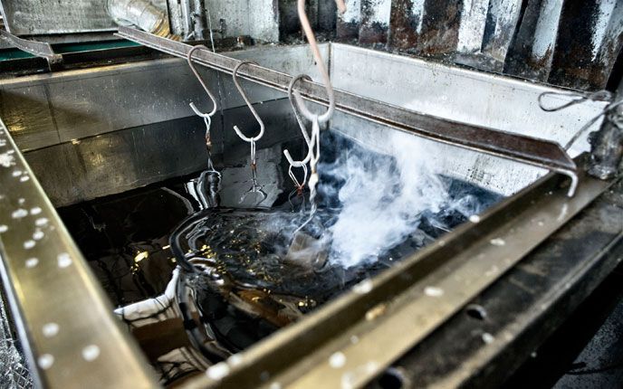 Un oggetto metallico viene pulito in una macchina da cui esce del fumo Tecma Brescia Nitrocarburazione Ferritica