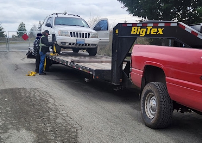 A red truck is towing a white suv on a big tex trailer - Blazin Trailz