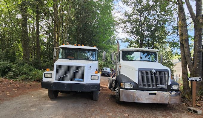 Two trucks are parked next to each other on a dirt road.