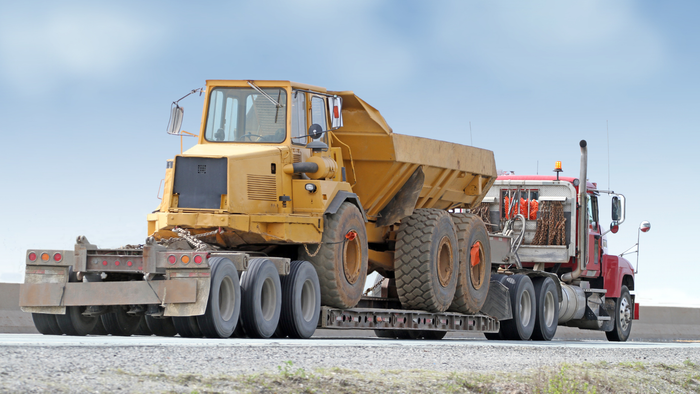 A large yellow dump truck is being towed by a semi truck - Blazin Trailz LLC