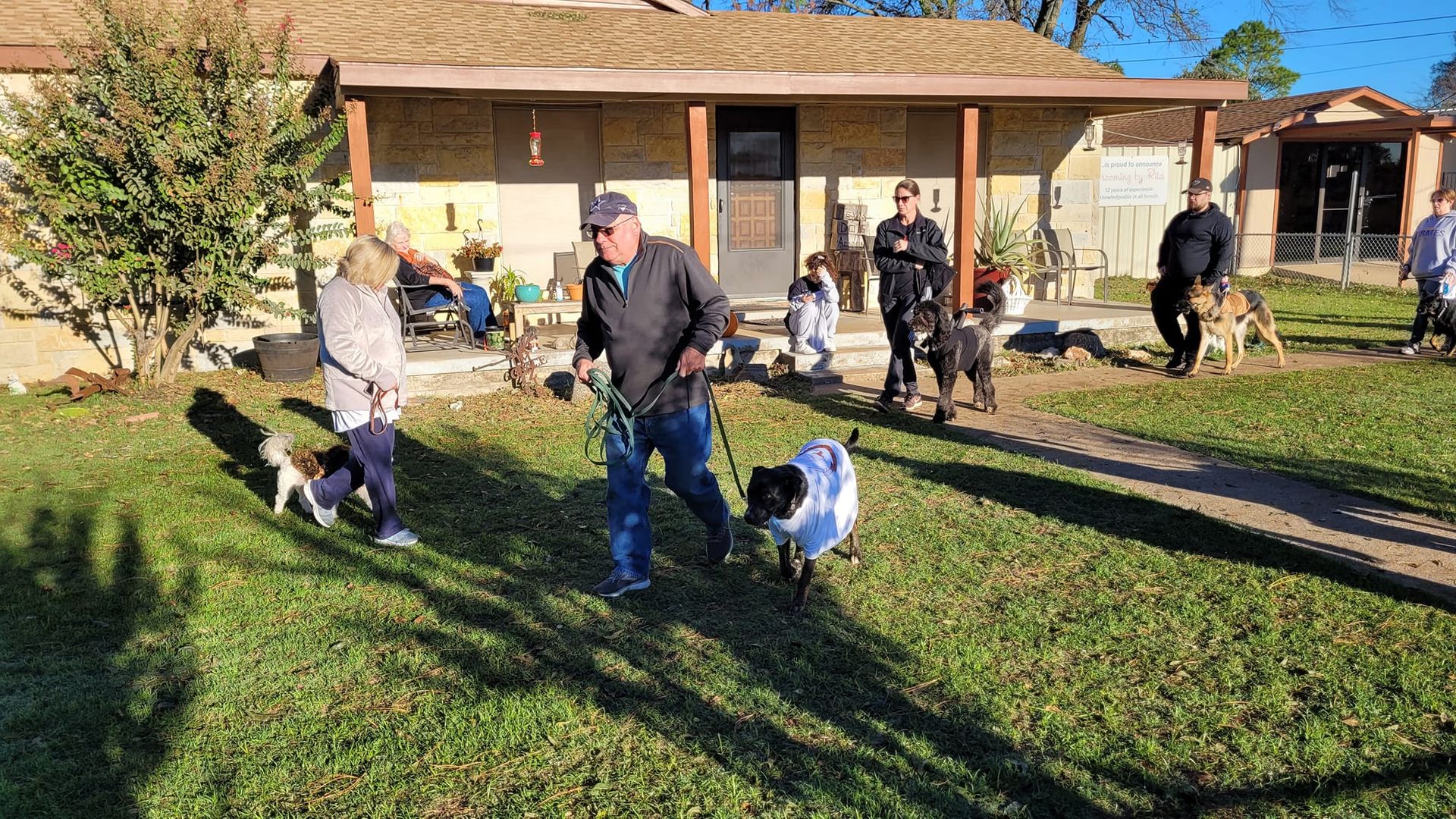 A group of people are walking dogs in front of a house.