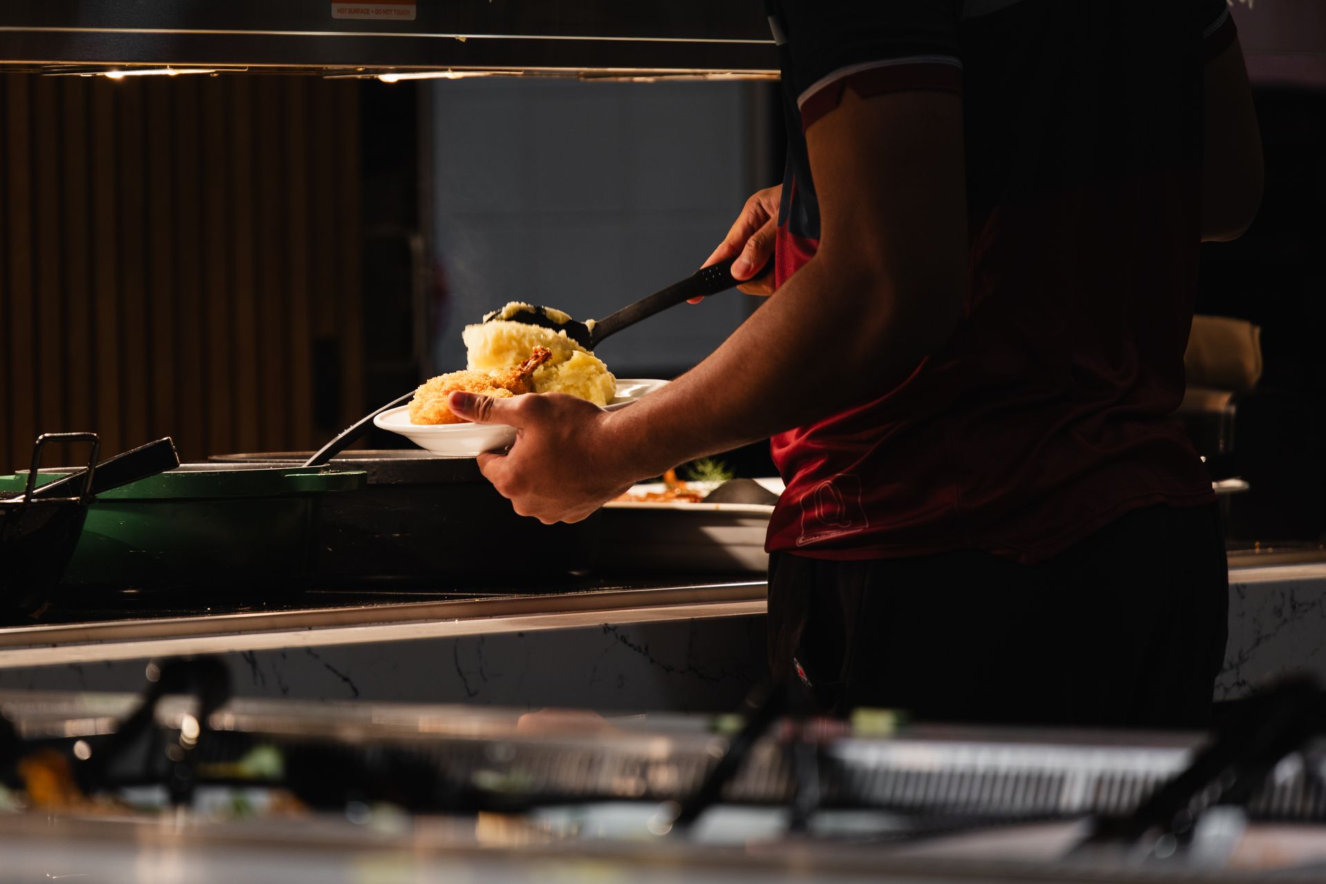 Student serving themselves dinner at a buffet.