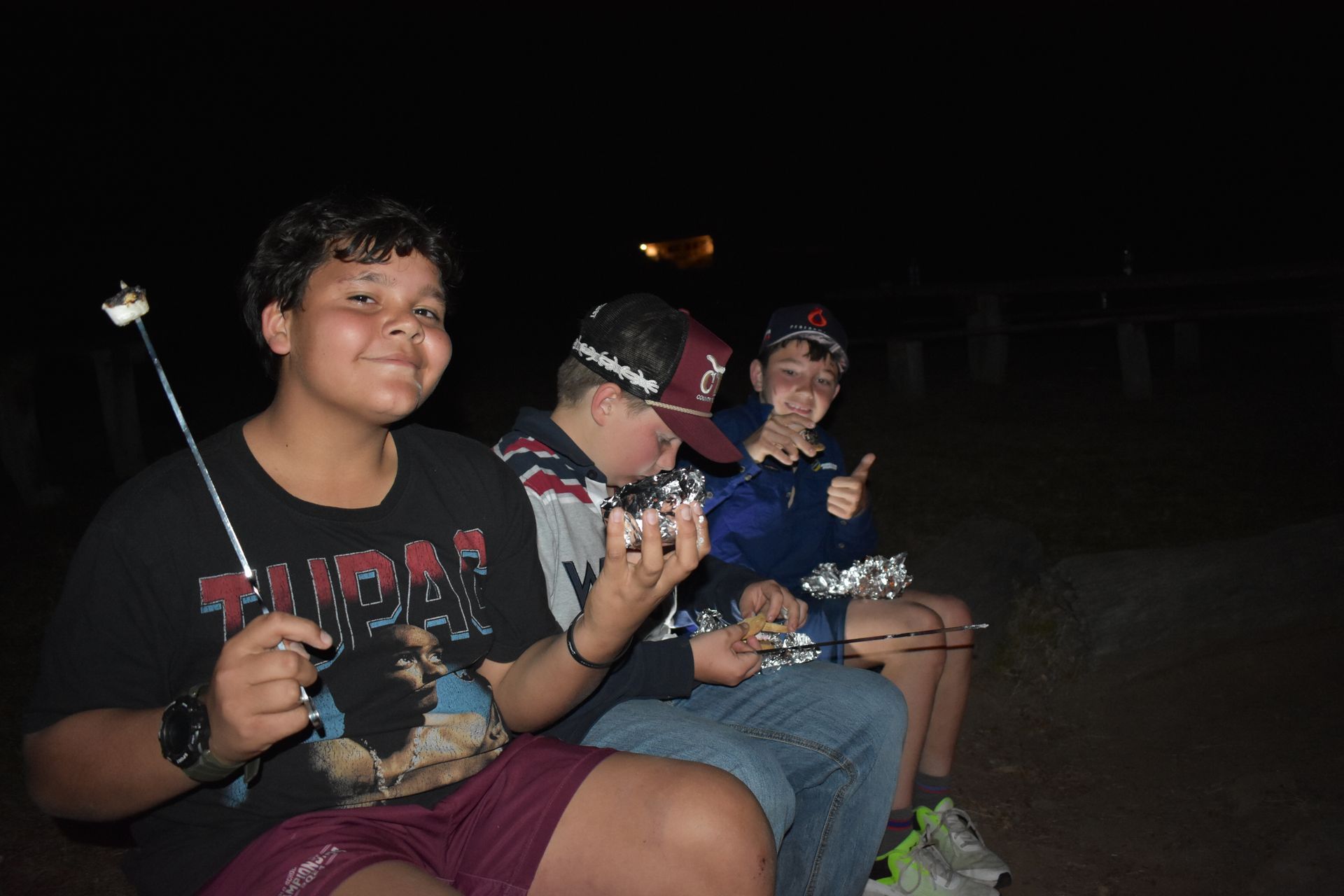 Three boarding students at a campsite with food they had toasted over an open campfire. 