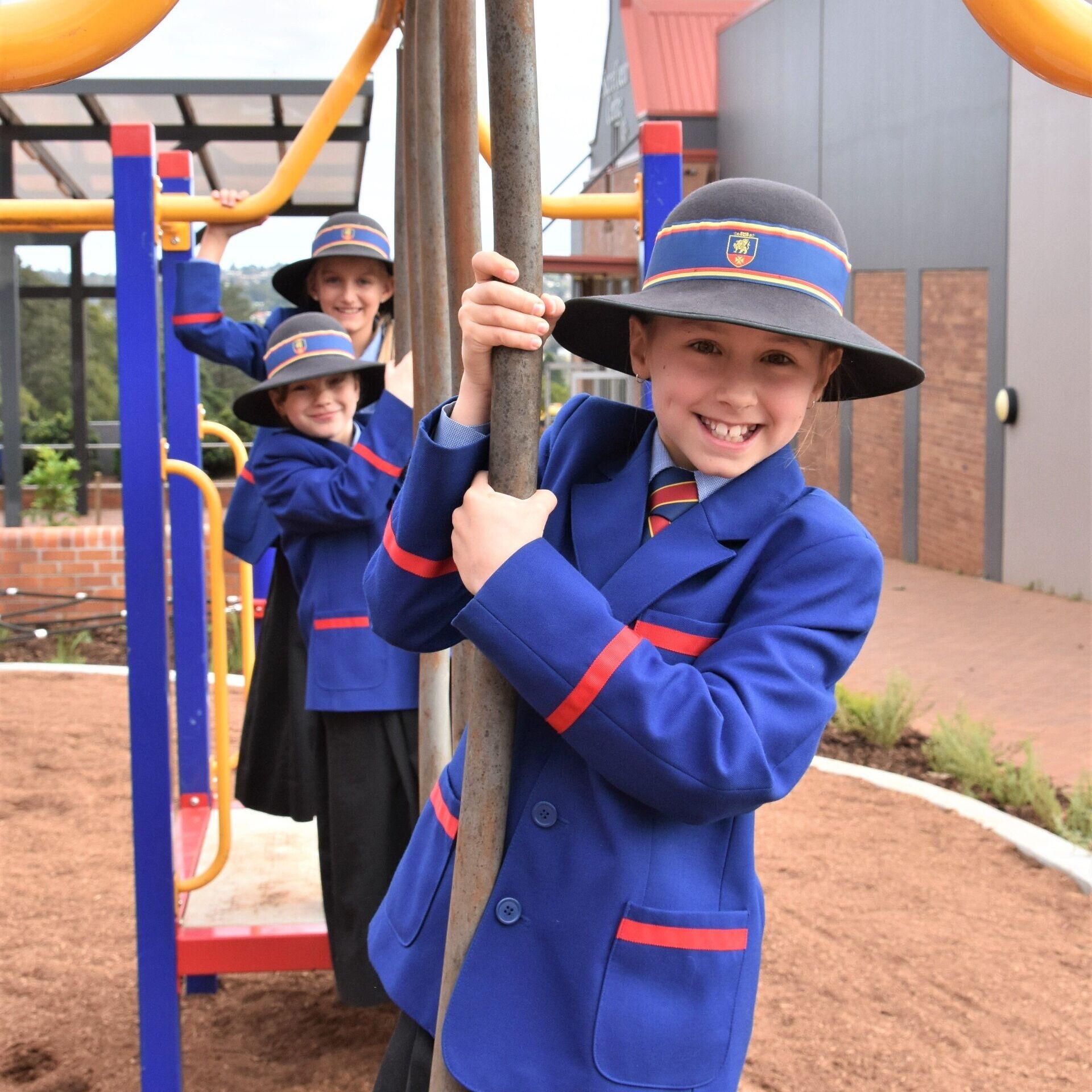 A schoolgirl in a blue jacket and hat playing on a playground