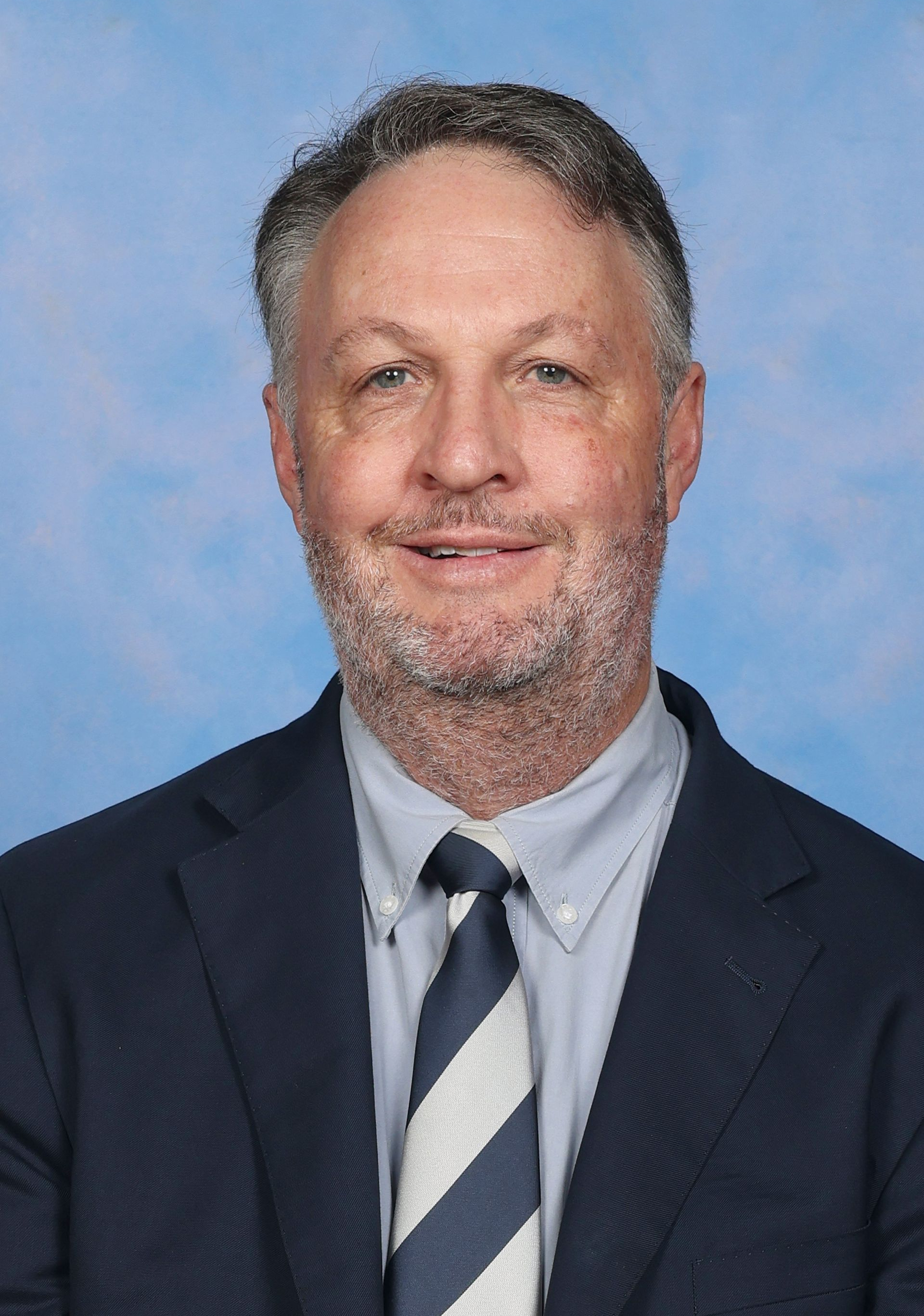 A man in a suit and tie is smiling for the camera