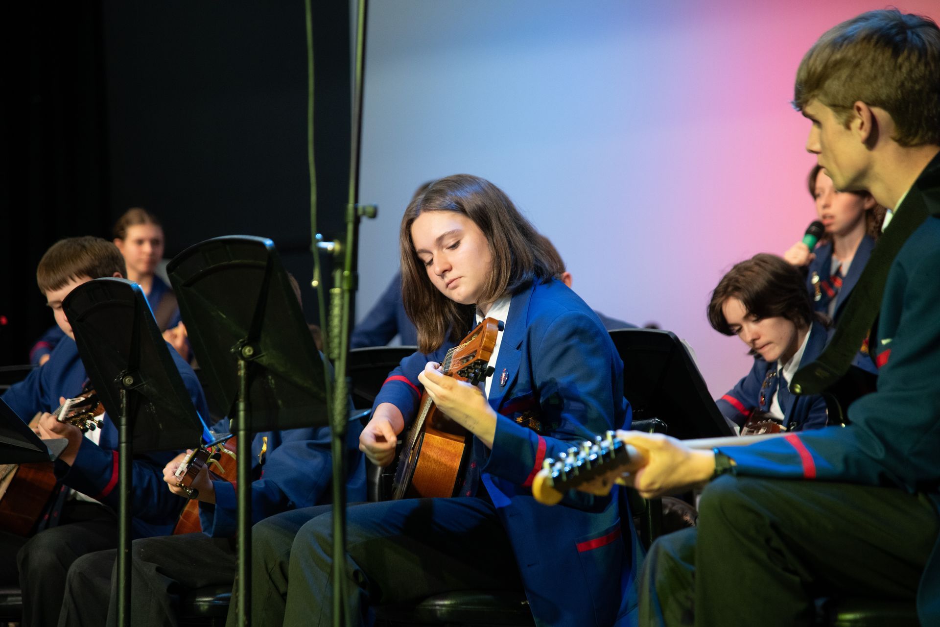 Students playing guitar on stage.