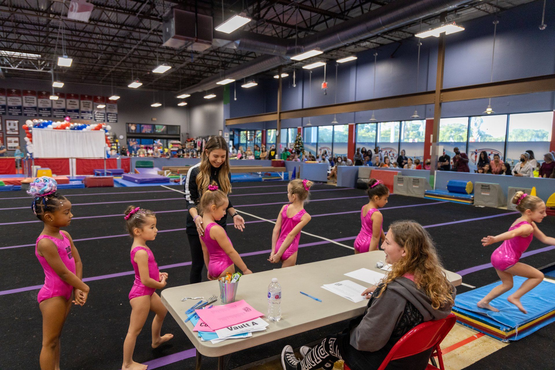 A group of young girls are standing around a table in a gym.