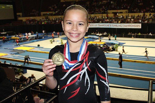 A young girl is holding a gold medal around her neck