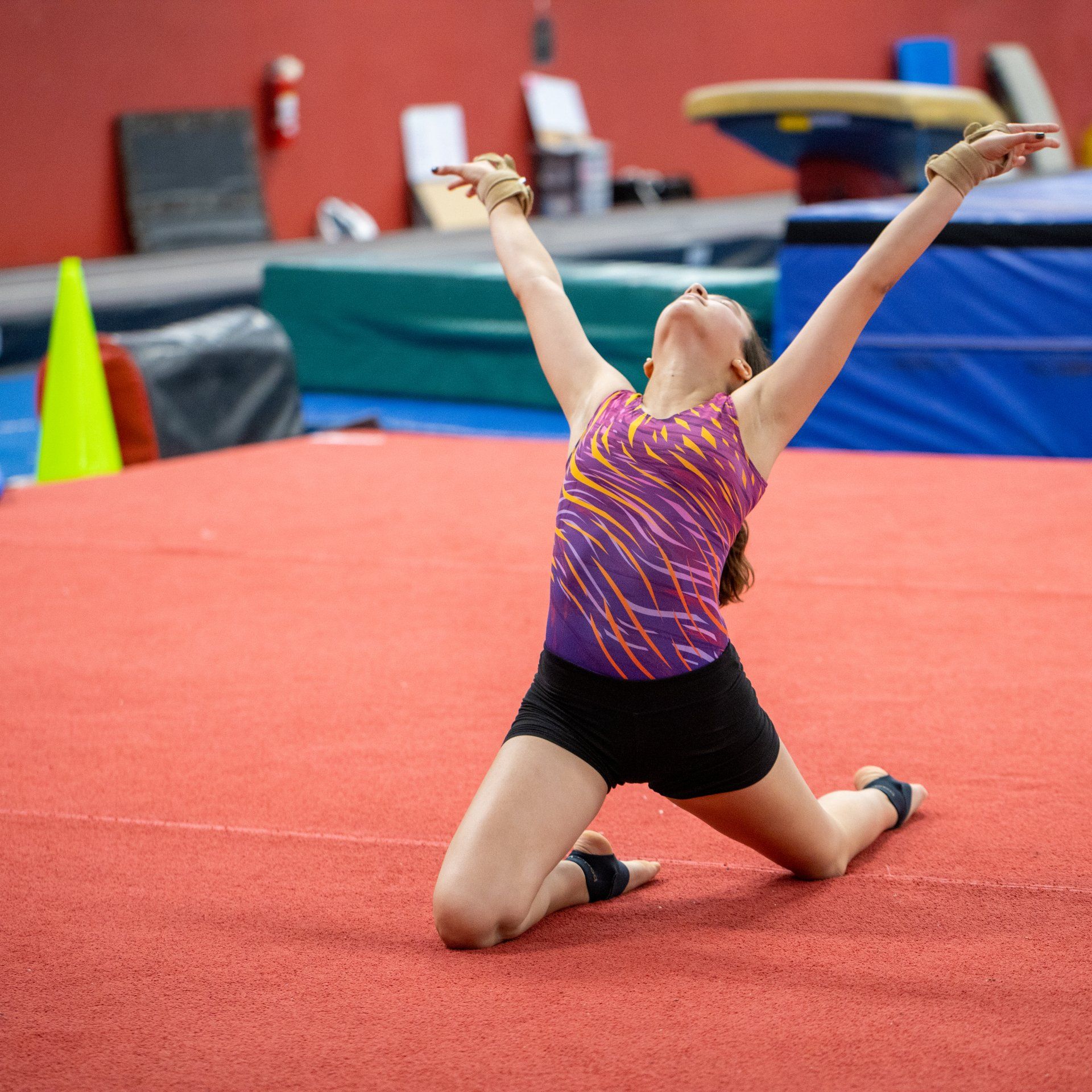 A woman is kneeling on the floor with her arms outstretched