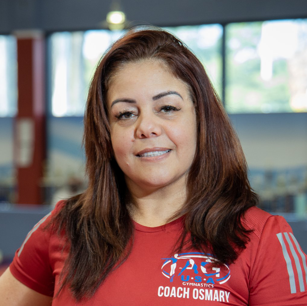 A woman wearing a red coach osmary shirt is smiling for the camera.