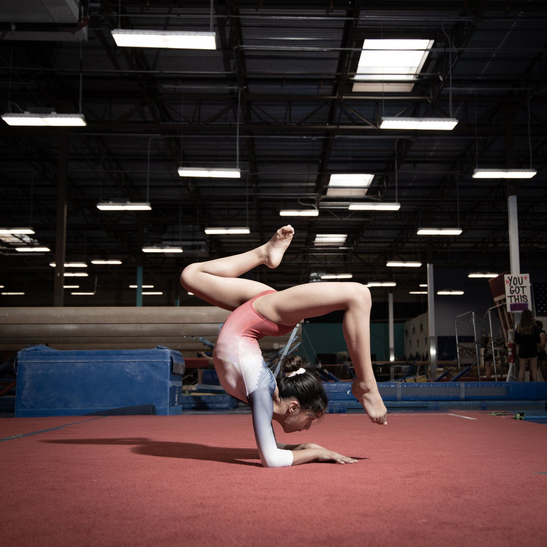 A female gymnast is doing a handstand on the floor