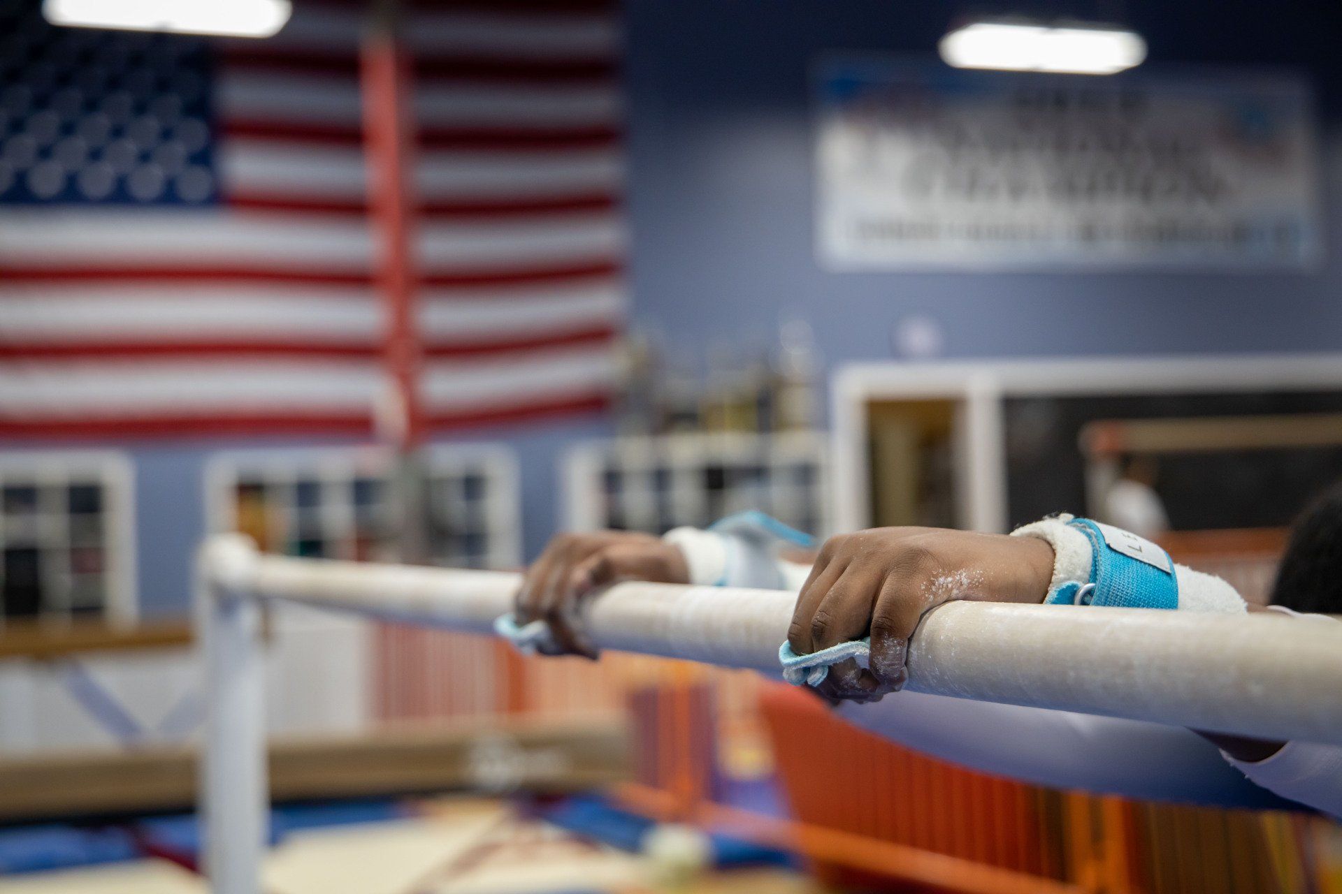A person is leaning on a balance beam in a gym.