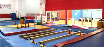 A gym with a lot of equipment and a row of balance beams.