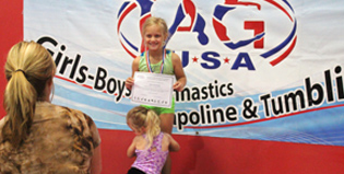 A girl is standing in front of a sign that says girls boys gymnastics poline & tumbling