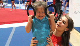 A woman is holding a little girl on gymnastic rings.