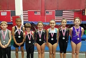 A group of young gymnasts are posing for a picture in a gym.