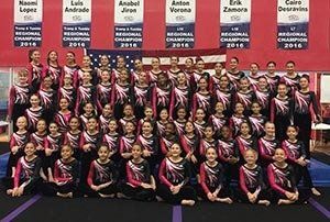 A group of gymnasts are posing for a picture in a gym.
