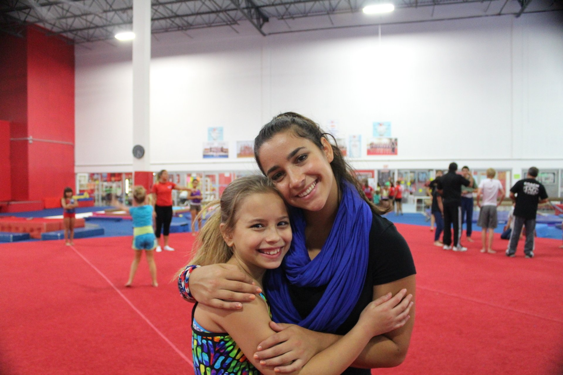 A woman is hugging a little girl in a gym.