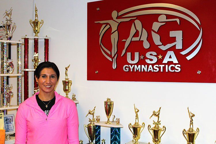 A woman stands in front of a usa gymnastics sign