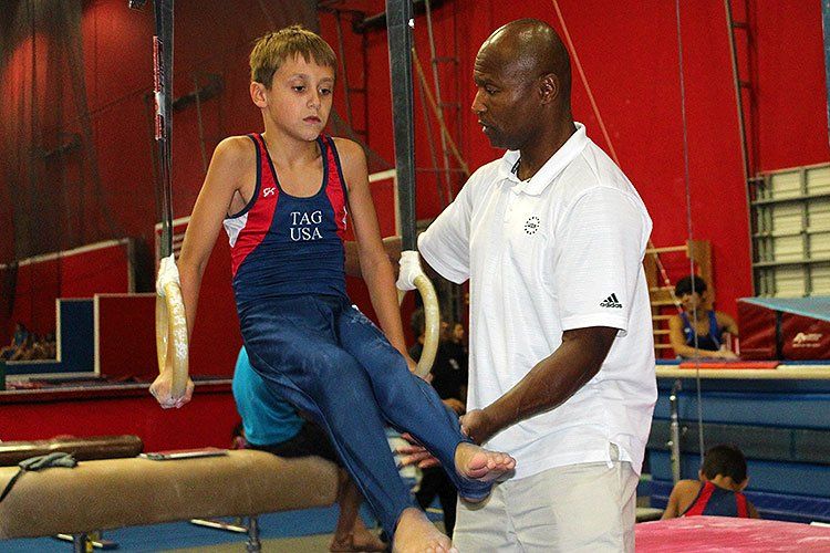 A man is helping a young boy on a balance beam