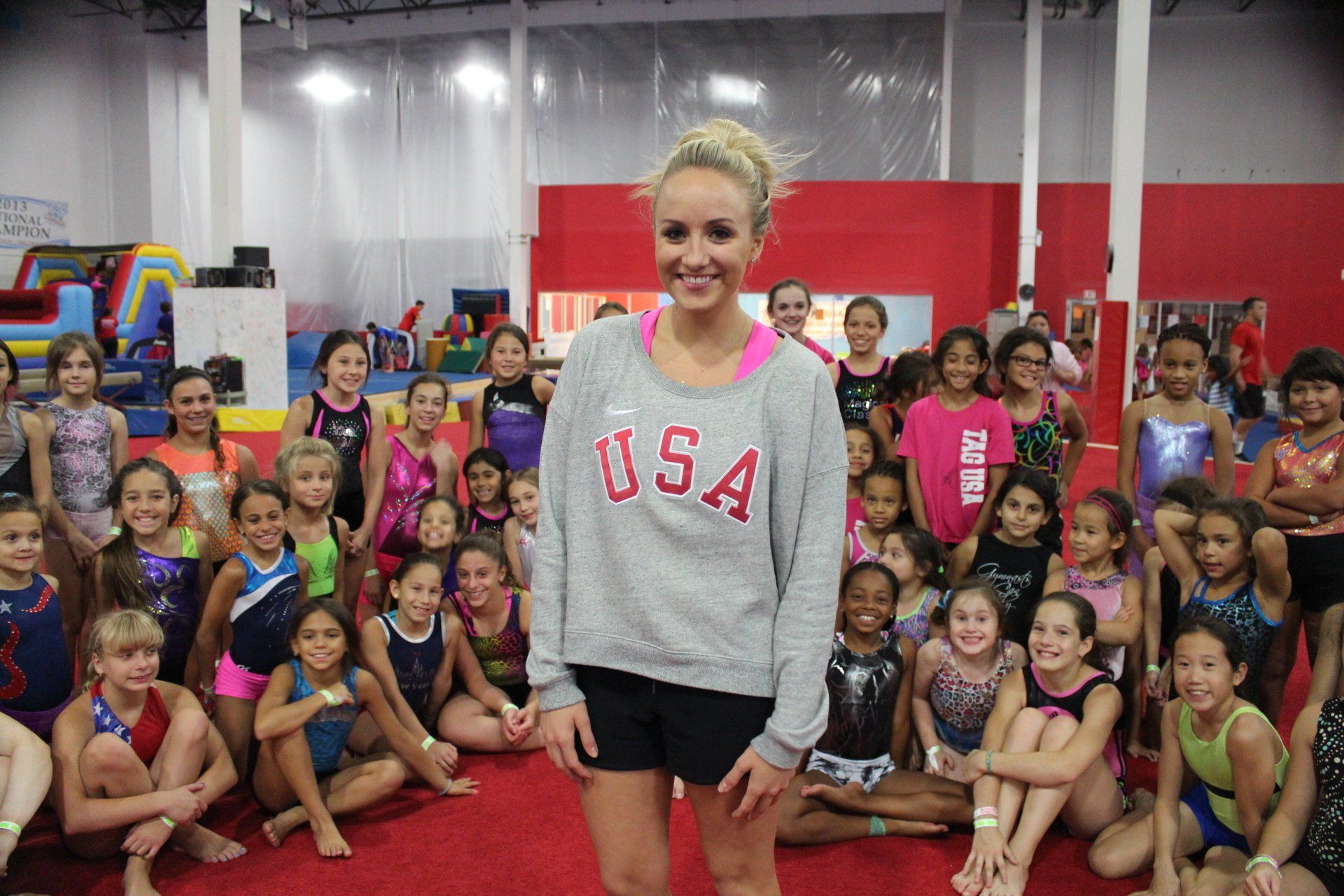 A woman wearing a usa sweatshirt is standing in front of a group of young girls.