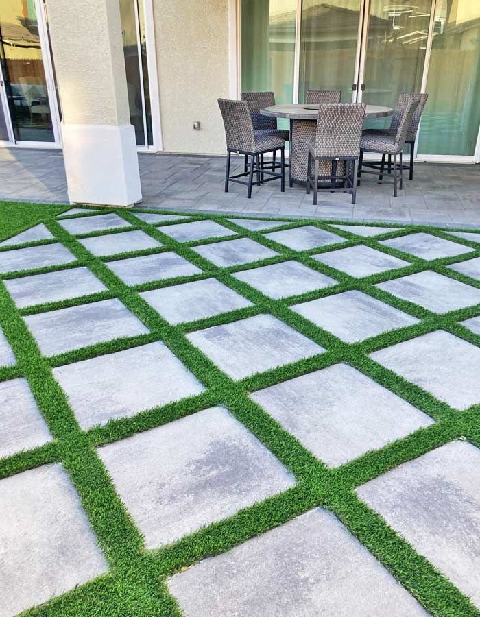 Concrete pavers with artificial turf in a grid pattern. Patio furniture on a concrete patio.