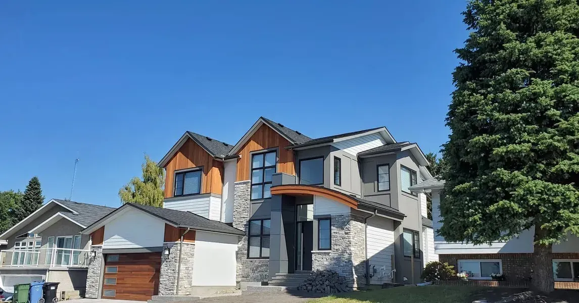 Modern two-story house with gray siding, orange wood accents, and a blue sky background