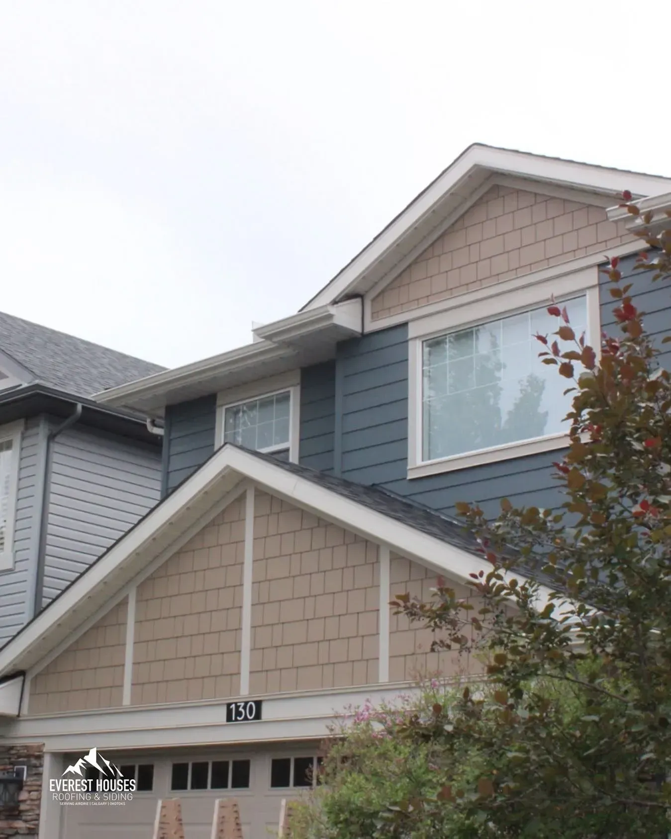 Two-story suburban house with beige and blue siding and a white gabled roof