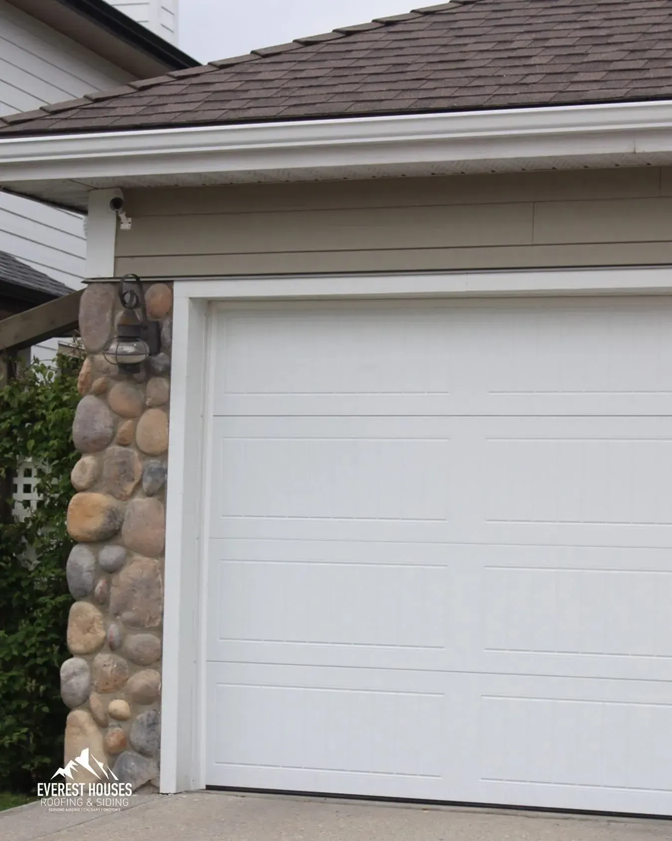 White garage door beside a stone pillar on a house exterior