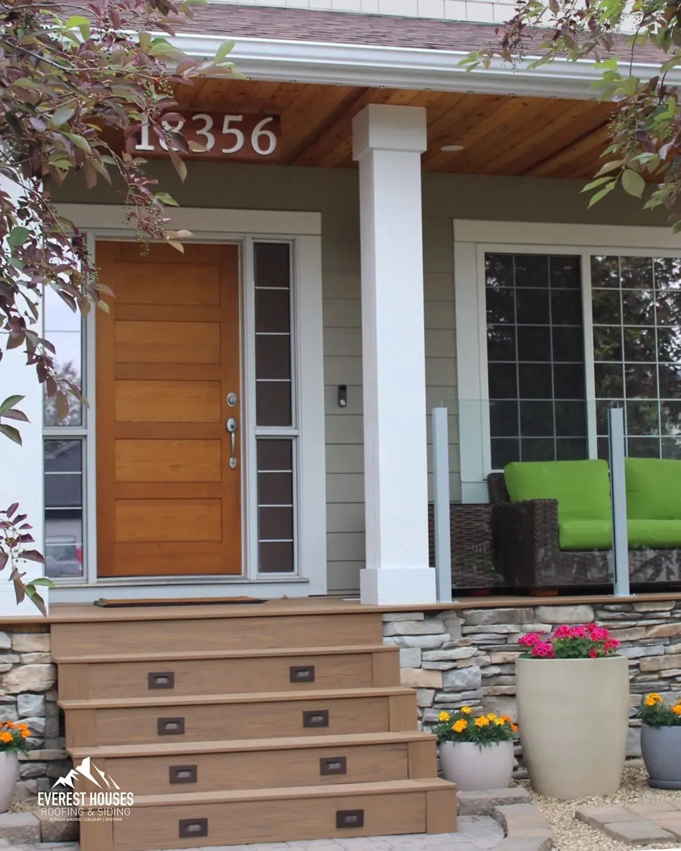 Front porch with wooden door, white columns, stone accents, potted flowers, and number 1356 above the entrance