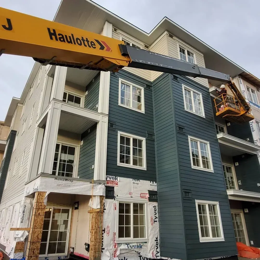 Construction lift beside a blue-and-white multi-story building under renovation