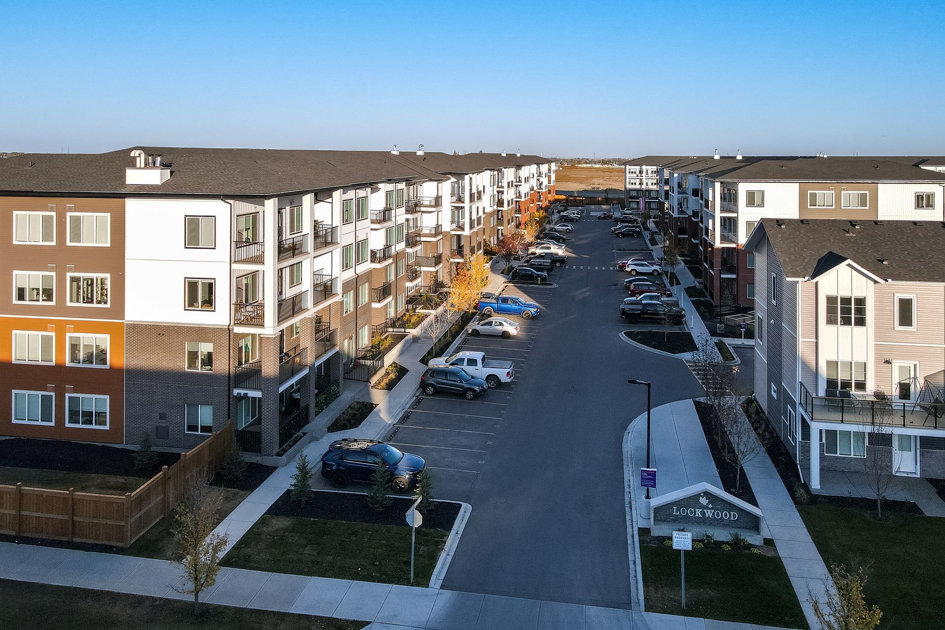 Aerial view of a residential street with apartment buildings and parked cars on both sides
