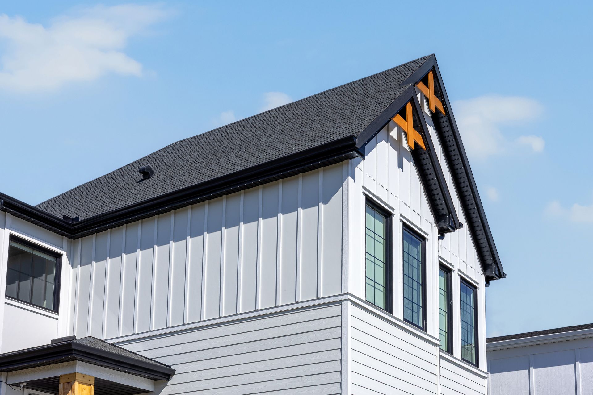 White house exterior with black roof and orange trim against a blue sky